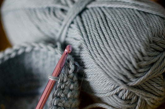 A crochet hook resting in a half-finished project of soft cream yarn