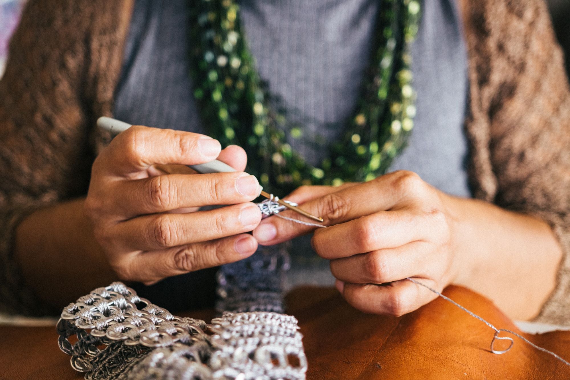 Mature woman's hands crocheting with an ergonomic hook - Caldova